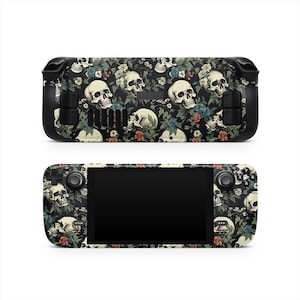 May include: A black handheld gaming device with a floral and skull pattern. The design features white skulls, blue and red flowers, and green leaves on a black background. The device has a screen and control buttons.