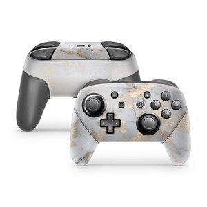 May include: A white and gold marble patterned Nintendo Switch controller. The controller has black buttons and joysticks.