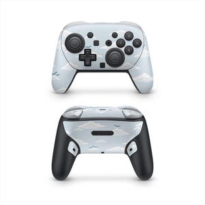 May include: A light blue and white controller with a cloud and bird design. The controller has black buttons and joysticks. The Nintendo logo is visible on the back of the controller.