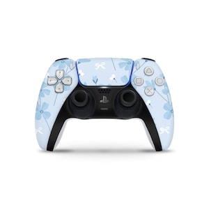 May include: A light blue PlayStation 5 controller with a floral pattern of blue flowers and white bows. The controller has black handles and buttons with the PlayStation symbols.