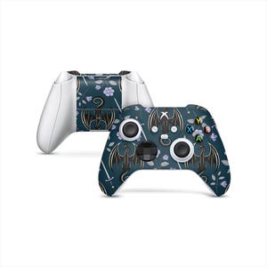 May include: Two Xbox controllers. One is white, the other is dark teal with a dragon and floral pattern. The dragon design is black with outstretched wings. The pattern includes swords and purple flowers. The buttons are colored.