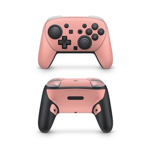May include: A coral-colored video game controller with black and white accents. The controller features a directional pad, buttons, and analog sticks. The back of the controller has the Nintendo logo.