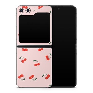 Può includere: Una custodia per telefono rosa con un motivo di ciliegie rosse. La custodia è progettata per un telefono pieghevole con una copertina anteriore.