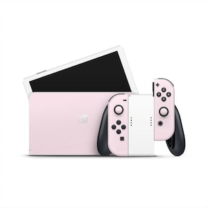 May include: A pink Nintendo Switch console with matching Joy-Con controllers. The console has a black screen and a white frame. The controllers are pink with black accents and buttons. The Switch is designed for portable and home gaming.