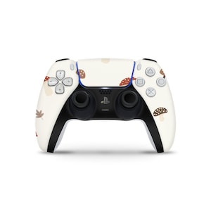 Könnte beinhalten: Ein weißer PlayStation 5 DualSense-Controller mit einem Pilz- und Blattmotiv. Der Controller hat schwarze Tasten und Trigger.