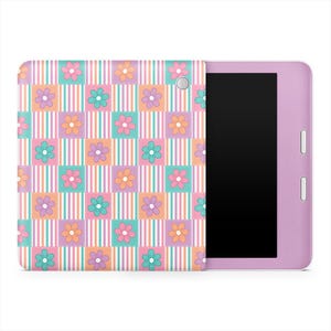 以下が含まれることがあります： ラベンダー色のタブレットと花柄のカバー。カバーは、ピンク、ティール、オレンジの正方形のパッチワークデザインで、それぞれに花があります。コーディネートされた色の縦縞が正方形の間のスペースを埋めています。