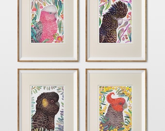 May include: Four framed watercolor prints featuring colorful parrots. Each print showcases a different parrot species, surrounded by botanical elements. The frames are gold-toned, and the artwork is set against a white background. The prints are labeled "Wild Garden".