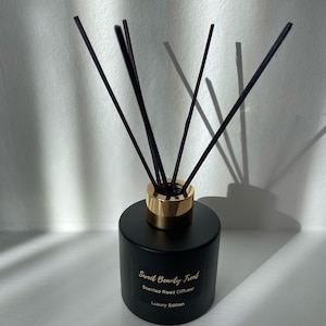 May include: Black glass bottle with gold accents and black reeds. The bottle has a label that reads "Sweet Beauty Treat Scented Reed Diffuser Luxury Edition".