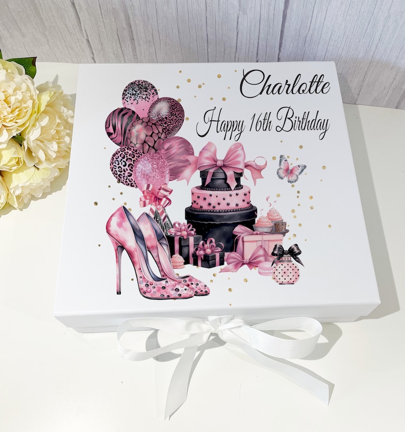 May include: White gift box decorated with pink high heels, balloons, a tiered cake, and gifts. The text "Charlotte Happy 16th Birthday" is printed on the box. A white ribbon is tied around the box.
