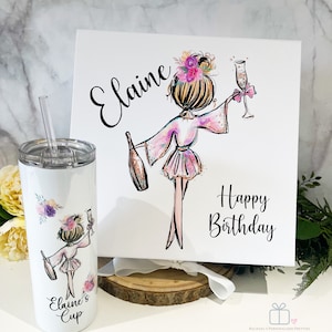 K&ouml;nnte beinhalten: Ein wei&szlig;er Becher mit einem Strohhalm und einem rosa-violetten Blumendesign. Der Becher zeigt ein Cartoon-Bild einer Frau im Bademantel, die ein Glas Champagner h&auml;lt. Der Text "Elaine's Cup" ist auf den Becher gedruckt. Eine wei&szlig;e Box mit einem rosa-violetten Blumendesign und dem Text "Elaine Happy Birthday" befindet sich im Hintergrund.