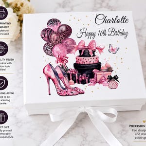 May include: A white gift box with a watercolour design featuring pink high heels, balloons, a cake, and the text "Charlotte Happy 16th Birthday." The box has a white ribbon and bow.
