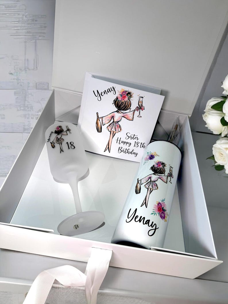 K&ouml;nnte beinhalten: Eine wei&szlig;e Geschenkbox mit einem wei&szlig;en Band. In der Box befindet sich eine wei&szlig;e Karte mit einer Zeichnung einer Frau, die ein Glas Champagner h&auml;lt. Die Karte sagt "Yenay Sister Happy 18th Birthday". Au&szlig;erdem gibt es ein wei&szlig;es Weinglas und einen wei&szlig;en Becher mit der gleichen Zeichnung und dem Namen "Yenay".