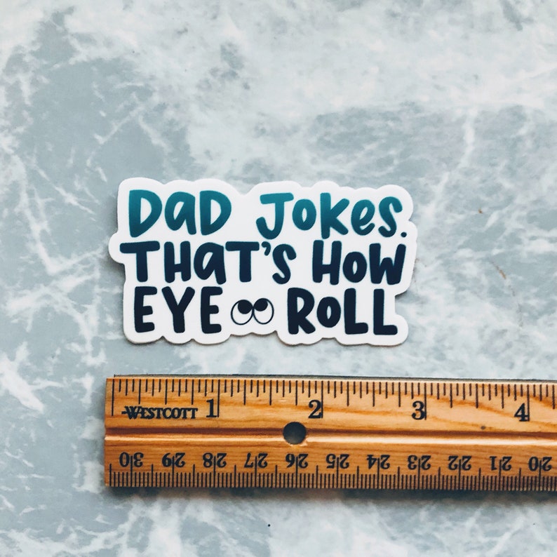 May include: A white sticker with blue and green text that reads "DAD Jokes. THAT'S HOW EYE ROLL" with two cartoon eyes in the middle of the text.