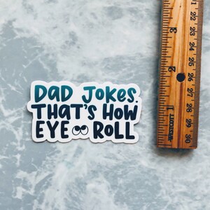 May include: White sticker with blue and teal text that reads "DAD Jokes. THAT'S HOW EYE ROLL" with two cartoon eyes in the word "EYE".