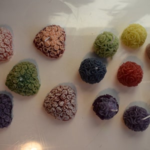 Candele decorate con rose a forma di palla e a forma di cuore nei colori viola, rosa, rosso, verde, giallo e blu