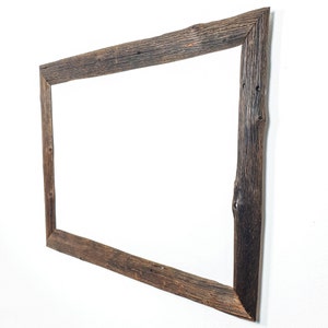 K&ouml;nnte beinhalten: Ein rustikaler Holzspiegelrahmen mit einer nat&uuml;rlichen Holzoptik. Der Rahmen ist rechteckig und aus recyceltem Holz mit Knoten und Unvollkommenheiten gefertigt.