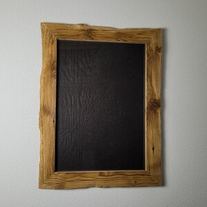 K&ouml;nnte beinhalten: Ein rustikaler Holzrahmen mit einer nat&uuml;rlichen Holzoptik und einem schwarzen Hintergrund. Der Rahmen hat eine raue, unebene Textur und eine leicht unregelm&auml;&szlig;ige Form.