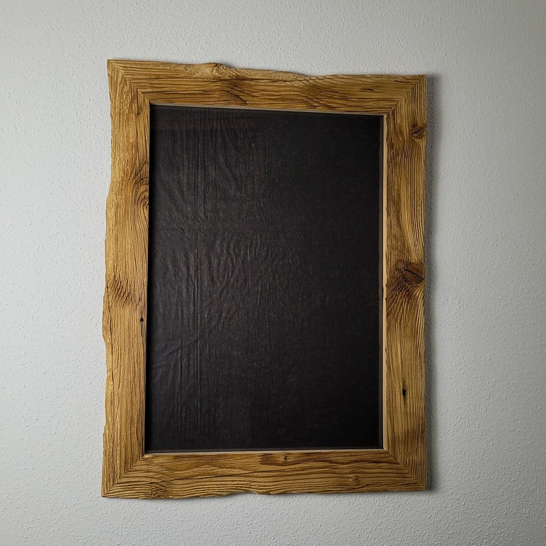 K&ouml;nnte beinhalten: Ein rustikaler Holzrahmen mit einer nat&uuml;rlichen Holzoptik und einem schwarzen Hintergrund. Der Rahmen hat eine raue, unebene Textur und eine leicht unregelm&auml;&szlig;ige Form.