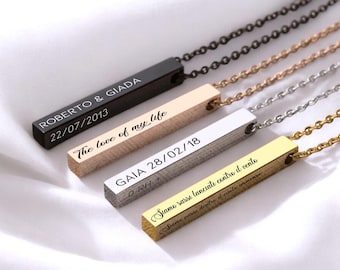 May include: Four personalized bar necklaces in black, gold, silver, and rose gold. Each pendant has engraved text, including names and dates. The necklaces hang on delicate chains, displayed on a white surface.