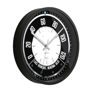 May include: A black and white wall clock with a speedometer design. The clock face features numbers from 0 to 120, with the text "km/h" and other Italian text. The clock has silver hands and a black bezel.