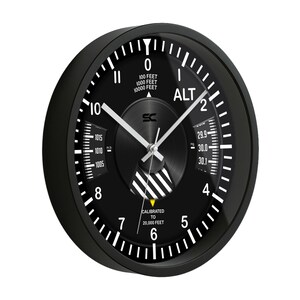 May include: Black analog wall clock with white markings and hands. The clock face features the word "ALT" and measurements in feet. The clock is calibrated to 20,000 feet.
