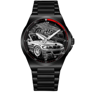 Op de afbeelding: Zwarte polshorloge met een gedetailleerde zilveren autografiek op de wijzerplaat. Het horloge heeft een zwarte band en lunette, met rode accenten en de tekst "E46". De wijzers van het horloge zijn zilver.