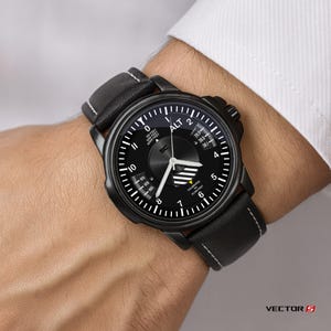 May include: Black wristwatch with a round face and a black leather band. The watch face features white markings and hands, with the word "ALT" at the top. The band has white stitching.