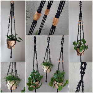 May include: Three black macrame plant hangers with wooden beads, each holding a potted plant. The hangers are made with a knotting technique and are hanging from the ceiling.