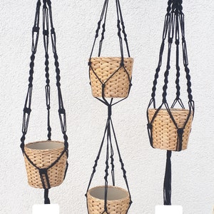 May include: Three black macrame plant hangers with woven baskets. The hangers are labeled 2c, 2er F., and 2a.