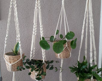 May include: Four macrame plant hangers with wooden rings and tassels hanging from a metal bar. Each hanger has a different plant in a woven basket. The hangers are labeled R9, KL, R7, and R3.