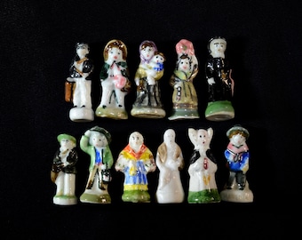 Puede incluir: Una colección de 12 pequeñas figuritas de porcelana, cada una representando a una persona diferente en varias poses y vestimentas. Las figuritas están pintadas en colores brillantes y tienen detalles elaborados.