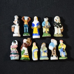 Puede incluir: Colección de pequeñas figuras de cerámica pintadas a mano que representan varias figuras con trajes tradicionales. Las figuras son coloridas, con detalles como ropa y accesorios. Cada figura mide aproximadamente 5 cm de altura.