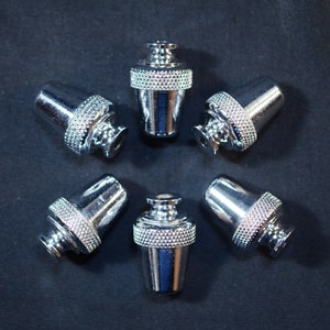 Może przedstawiać: Sześć srebrnych metalowych kołków do strojenia gitary z ozdobnym wzorem.