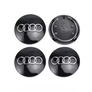 Könnte beinhalten: Vier schwarze Radnabenabdeckungen mit glänzendem Finish. Jede Kappe zeigt das silberne Audi-Logo, bestehend aus vier ineinandergreifenden Ringen. Eine Kappe zeigt die Rückseite mit dem Text "Germany".
