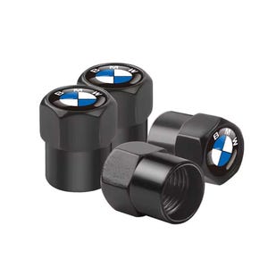 May include: Four black valve stem caps featuring the BMW logo in white and blue. The caps have a hexagonal shape and a glossy finish. The BMW logo is set against a blue background.