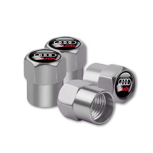 Peut inclure: Un ensemble de quatre bouchons de valve de pneu en métal argenté de forme hexagonale. Chaque bouchon présente un insert circulaire noir sur le dessus affichant le logo Audi à quatre anneaux blancs et le texte Audi en rouge au centre.