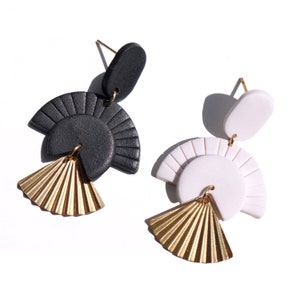 May include: A pair of geometric earrings with black and white clay shapes and gold fan accents.
