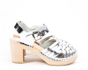 May include: Silver leather heeled sandals with a woven design and a wooden platform sole.