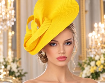 May include: A bright yellow fascinator hat featuring a wide, curved brim and structured, looped ribbon detailing. The hat is crafted from a textured, woven material and is positioned at an angle on the head, creating a bold, sculptural silhouette.