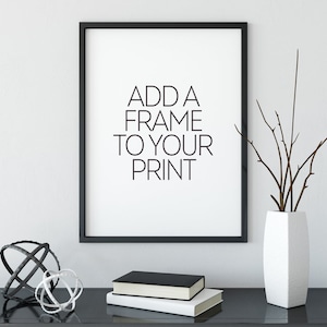 May include: A black framed print with the text "ADD A FRAME TO YOUR PRINT" on a white background. The print is sitting on a black table with a white vase and a decorative metal orb.