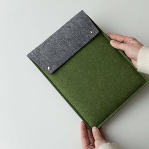 May include: A green felt laptop sleeve with a gray felt flap. The sleeve has two silver snaps.