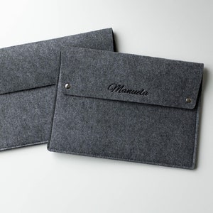 May include: Two gray felt laptop sleeves, one with the name "Manuela" embroidered on the front.
