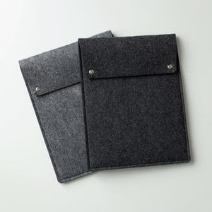 May include: Two felt envelopes, one gray and one black, with a flap and a button closure.
