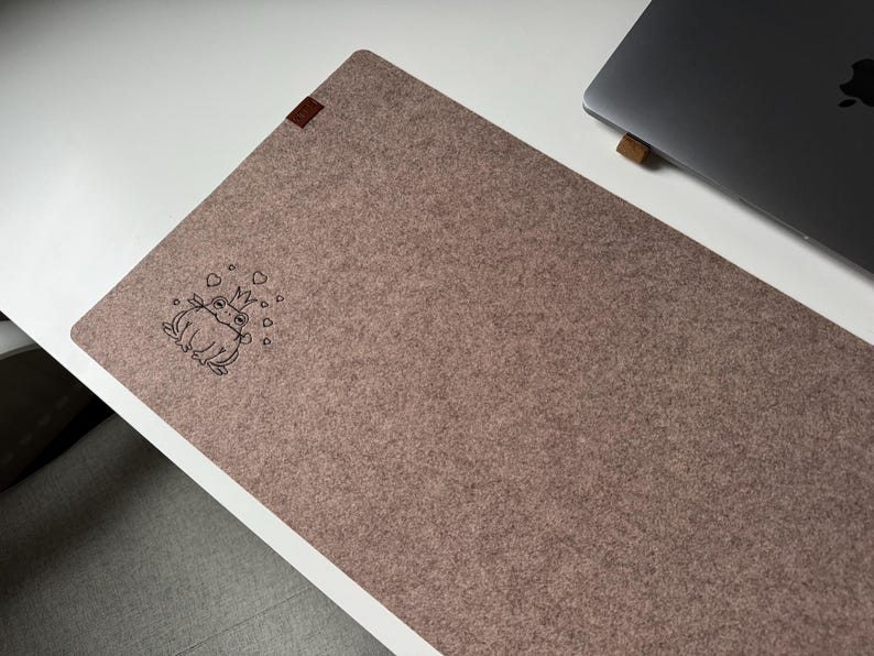 May include: A brown felt mouse pad with a black outline of a frog wearing a crown and surrounded by hearts.