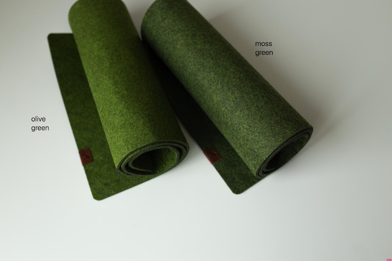 May include: Two rolled-up felt placemats in olive green and moss green. The placemats are rolled up and have a brown leather tag on the end.