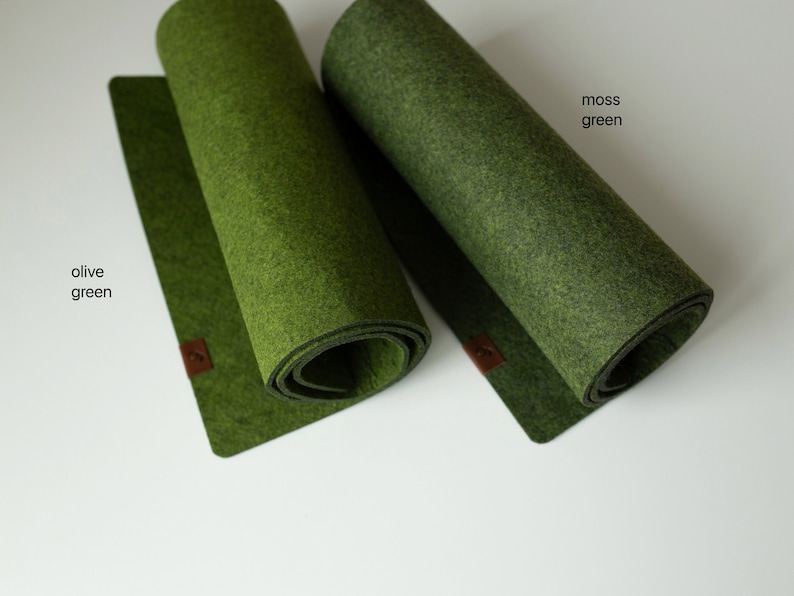 May include: Two felt placemats in different shades of green. The placemat on the left is olive green and the placemat on the right is moss green.