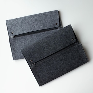 May include: Two gray felt zippered pouches. The pouches are stacked on top of each other. The top pouch is slightly lighter in color than the bottom pouch.
