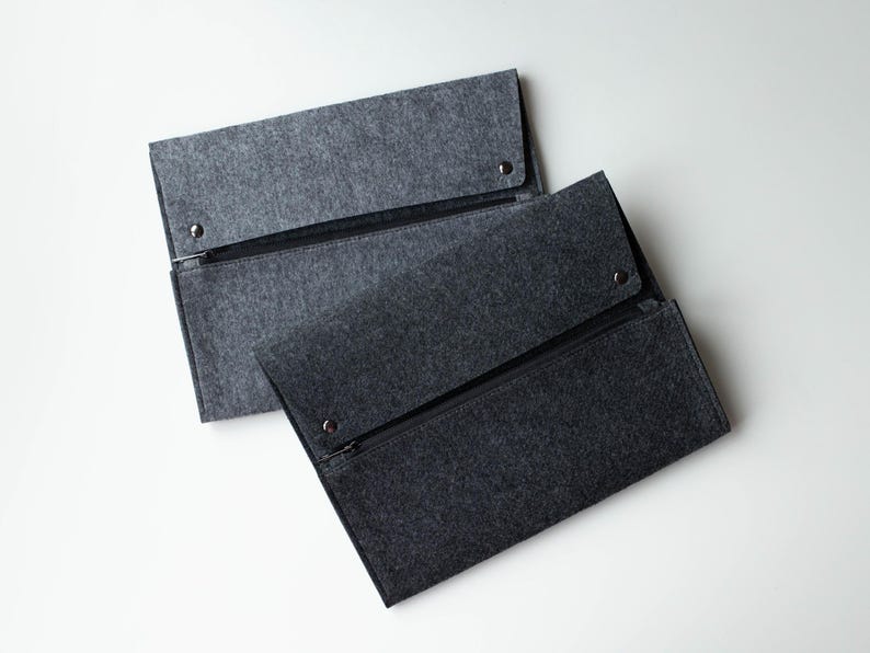 May include: Two gray felt zippered pouches. The pouches are stacked on top of each other. The top pouch is slightly lighter in color than the bottom pouch.
