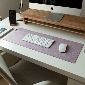 May include: A white desk with a light purple mouse pad, a white keyboard, a white mouse, a glass of water, and a book titled "So Good For You".