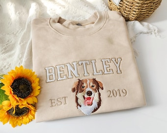 May include: Beige sweatshirt with embroidered text "Bentley Est 2019" and an embroidered image of a brown and white dog.
